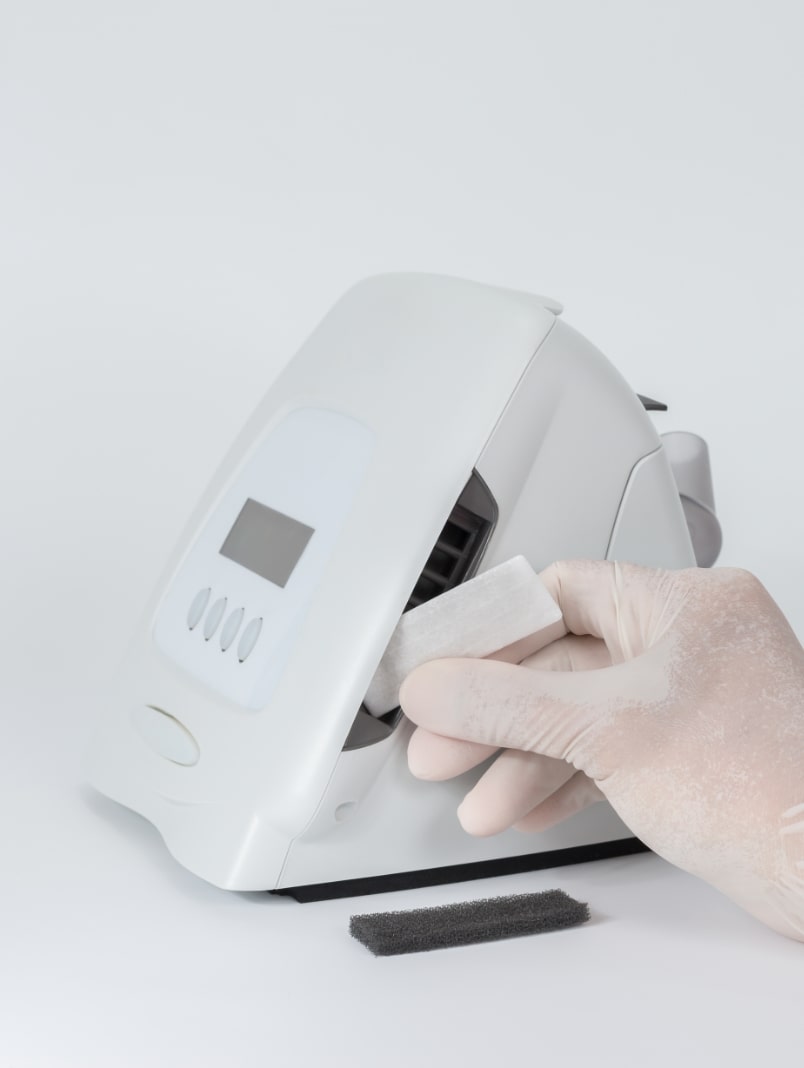 Ręka w rękawiczce czyści urządzenie medyczne przy pomocy chusteczki.