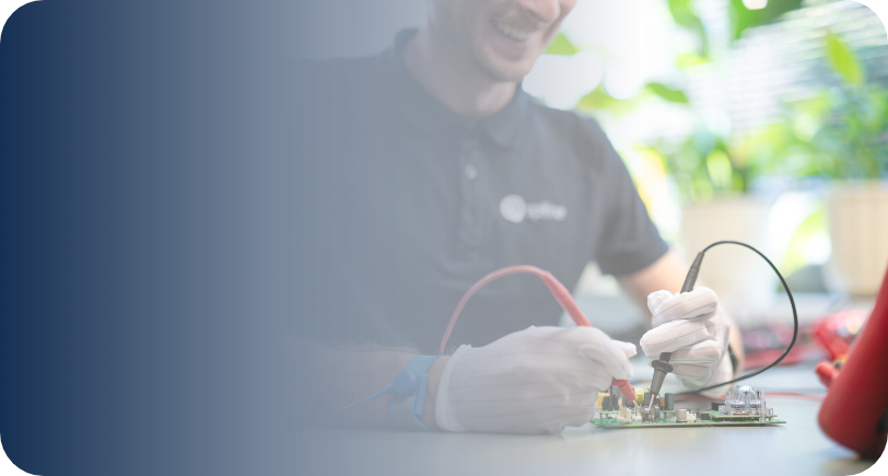 Mężczyzna w rękawiczkach naprawia płytę elektroniczną za pomocą sond pomiarowych.