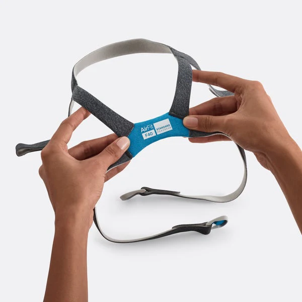 64634-AirFitF40-Headgear-STD_Hands_720x Dwie ręce trzymają opaskę do maski CPAP AirFit F40 na białym tle.
