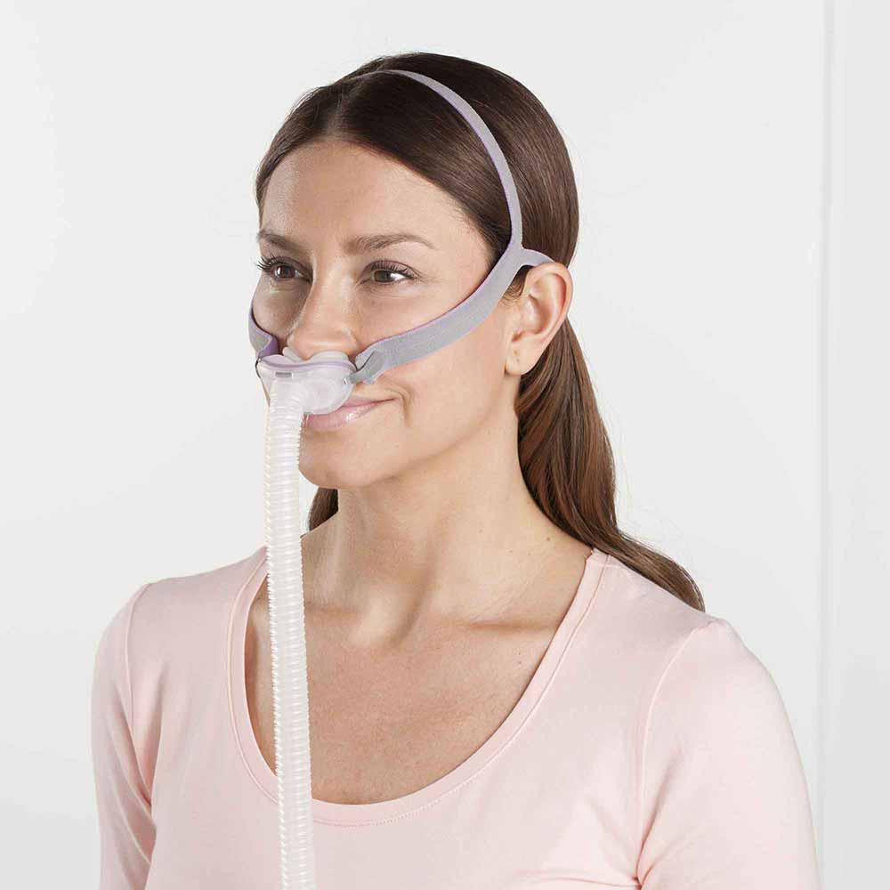 maska-donosowa-dla-kobiet-airfit-p10-for-her Kobieta nosi na twarzy maskę tlenową z rurką do terapii oddechowej.