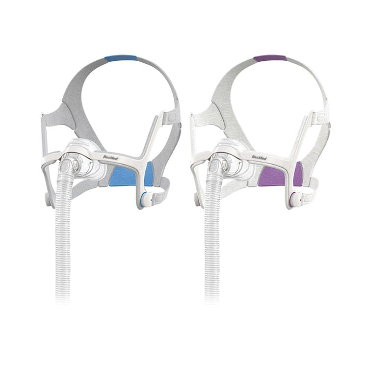 maska-nosowa-cpap-airfit-n20-resmed Dwa aparaty do terapii bezdechu sennego CPAP z rurkami, w kolorach niebieskim i fioletowym.