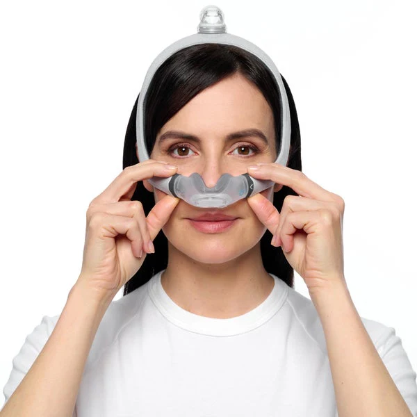 AirTouch-N30i-female Kobieta zakłada maskę do terapii CPAP na nos.