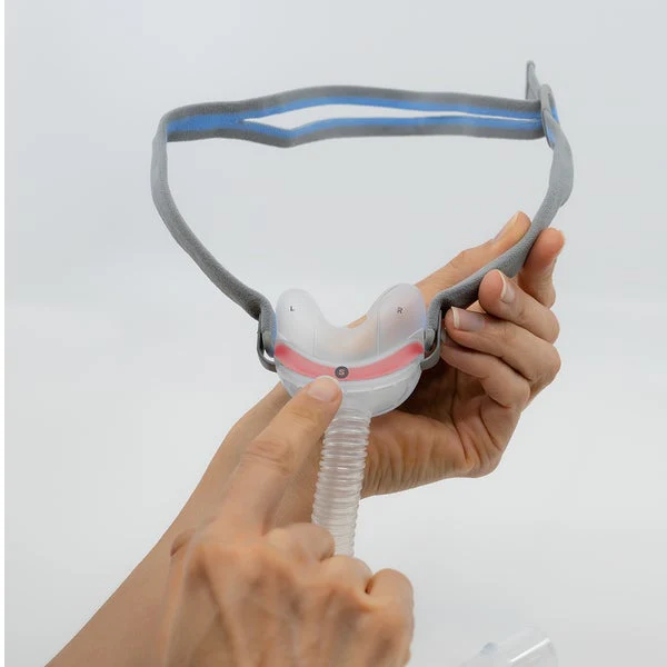 Maska-nosowa-AirFit-N30-ResMed-2 Osoba trzyma i wskazuje maskę do terapii CPAP z opaską na głowę.